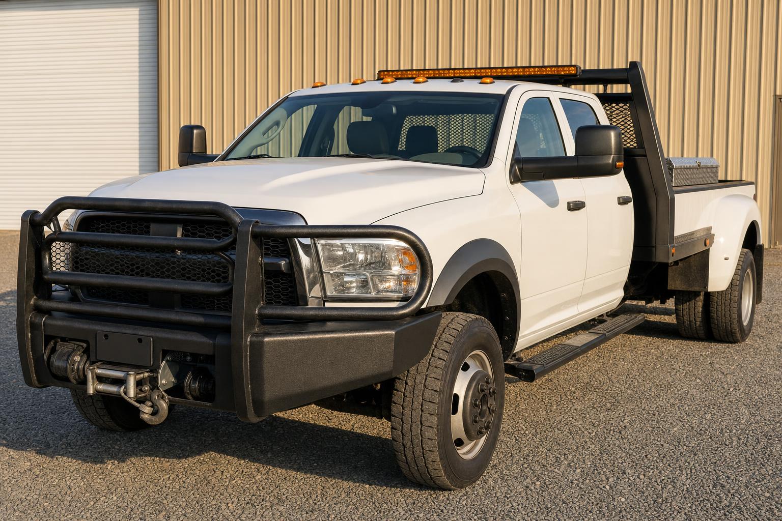 White pickup with a grille guard, winch, light bar, steps, headache rack, and toolbox